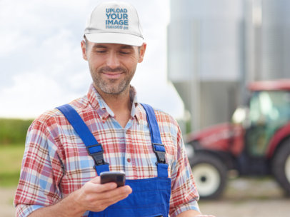 Dad Hat Mockup Featuring a Worker Checking His Mobile Phone 35705-r-el2